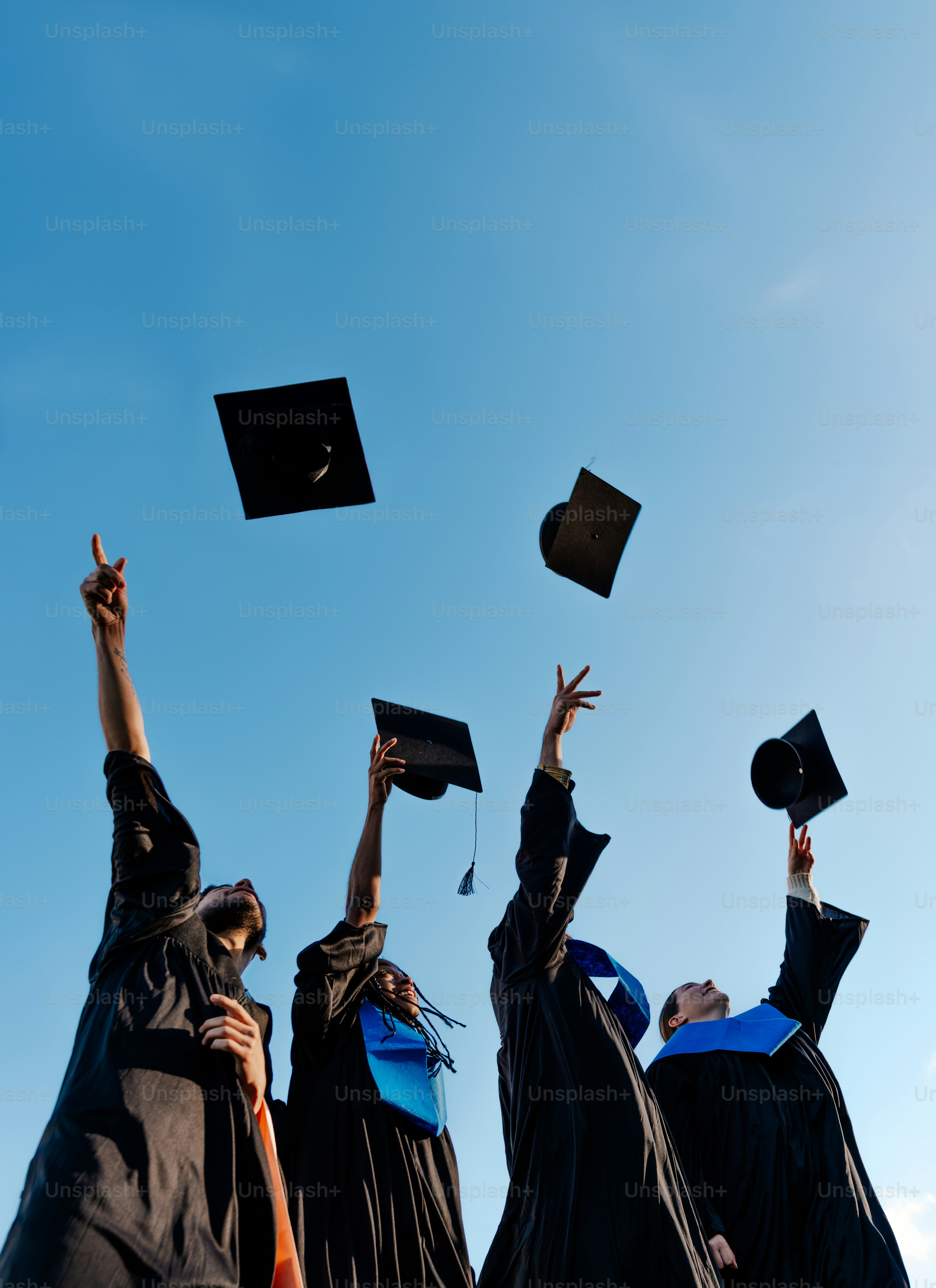 Graduates in caps and gowns tossing hats in the air.